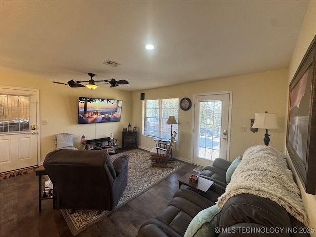 living room featuring ceiling fan and dark wood-type flooring