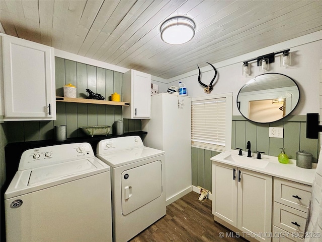 clothes washing area featuring dark hardwood / wood-style flooring, sink, wooden ceiling, cabinets, and separate washer and dryer