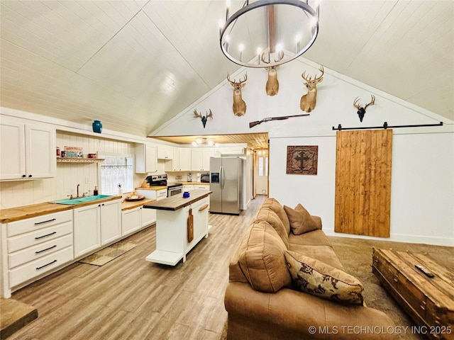 kitchen with white cabinetry, appliances with stainless steel finishes, butcher block counters, and a barn door