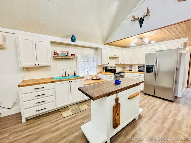 kitchen featuring butcher block counters, white cabinets, a kitchen island, sink, and stainless steel appliances