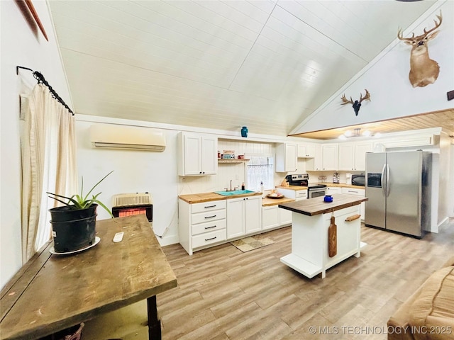 kitchen with wooden counters, appliances with stainless steel finishes, white cabinets, heating unit, and an AC wall unit