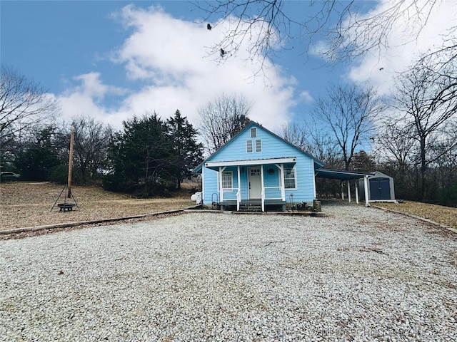 view of front of house featuring covered porch, a carport, and a storage unit