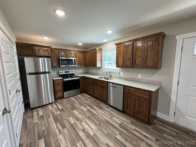 kitchen with appliances with stainless steel finishes, hardwood / wood-style flooring, and sink