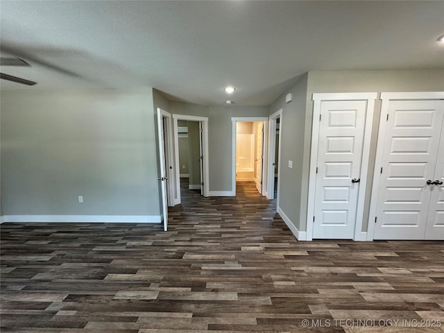 interior space featuring multiple closets, ceiling fan, and dark hardwood / wood-style flooring