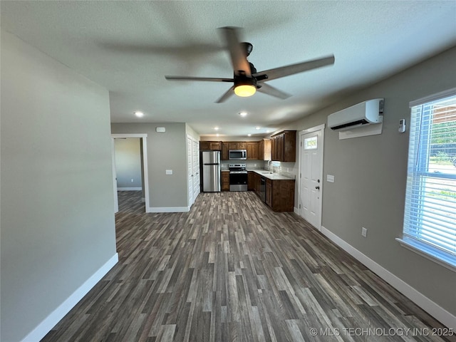 kitchen featuring dark hardwood / wood-style flooring, a textured ceiling, stainless steel appliances, a wall unit AC, and sink