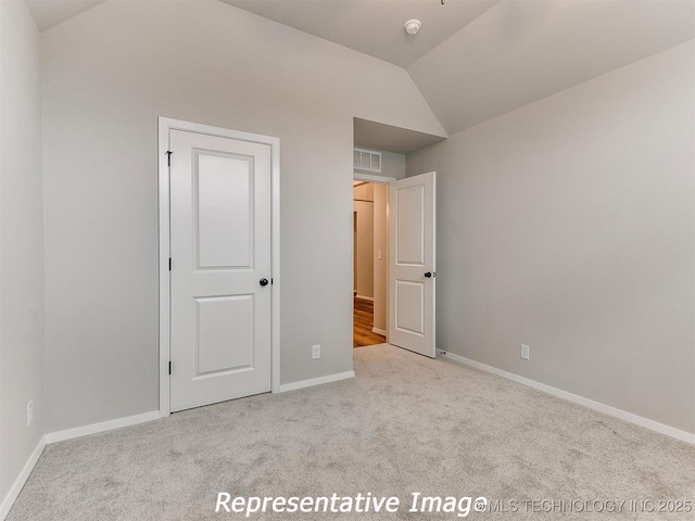 unfurnished bedroom with light carpet and vaulted ceiling