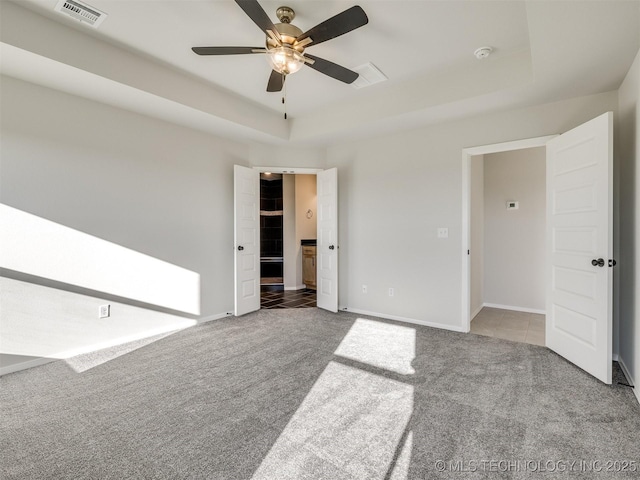 spare room with carpet flooring, ceiling fan, and a tray ceiling