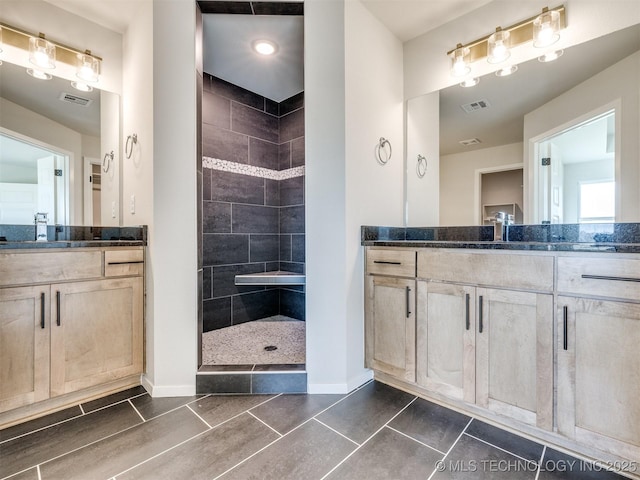 bathroom with tiled shower, vanity, and tile patterned floors