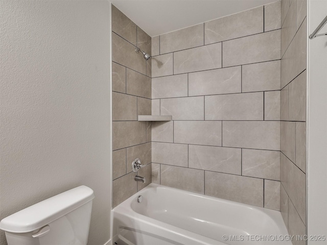 bathroom with toilet and tiled shower / bath