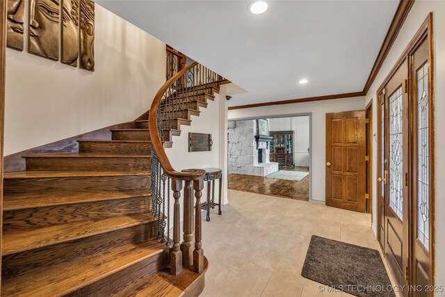 entryway featuring light tile patterned floors, a stone fireplace, ornamental molding, and french doors