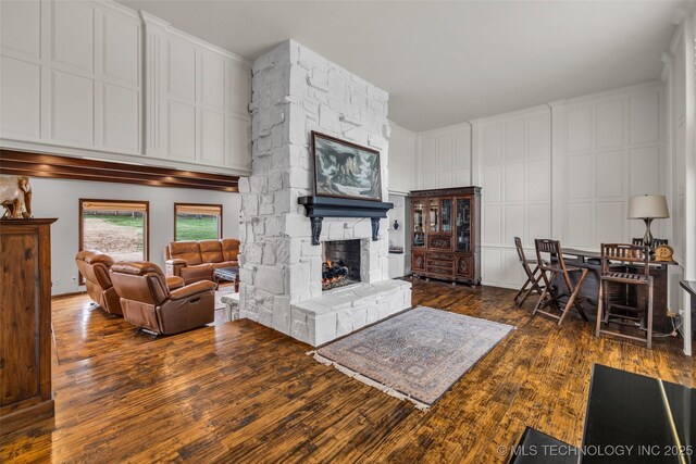 living room featuring dark wood-type flooring and a stone fireplace