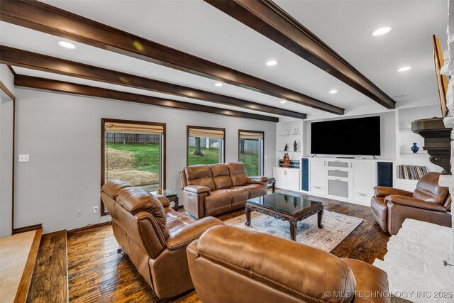 living room featuring beamed ceiling, wood-type flooring, a large fireplace, and built in features