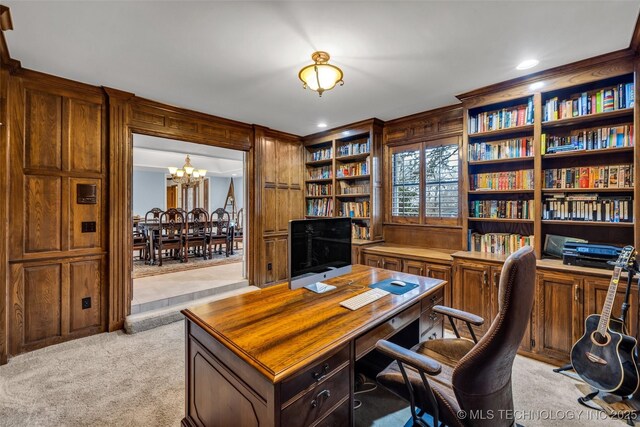 office space with an inviting chandelier, light carpet, and wooden walls