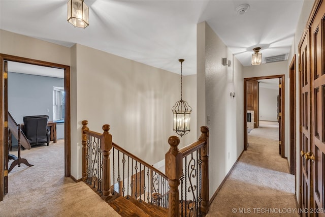 corridor with a notable chandelier and light colored carpet