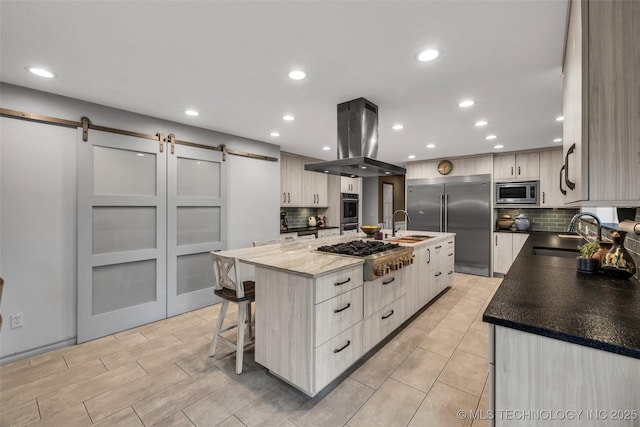 kitchen featuring a large island, sink, built in appliances, island exhaust hood, and a barn door