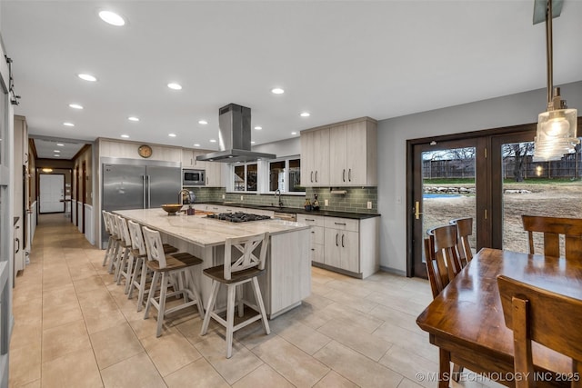 kitchen with built in appliances, decorative light fixtures, a center island, island exhaust hood, and decorative backsplash