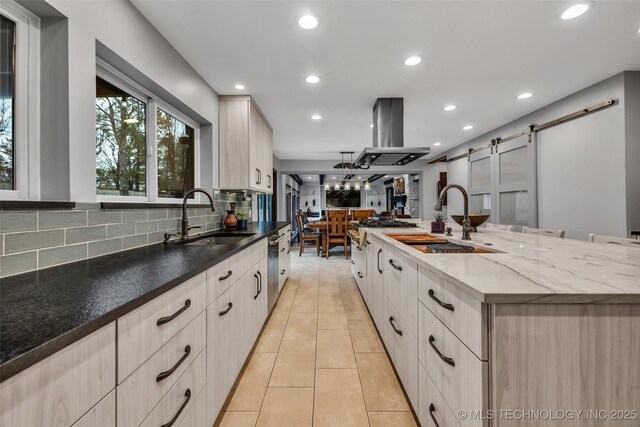 kitchen featuring a barn door, sink, island range hood, and a spacious island