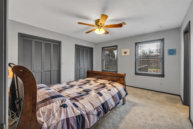 carpeted bedroom featuring two closets and ceiling fan