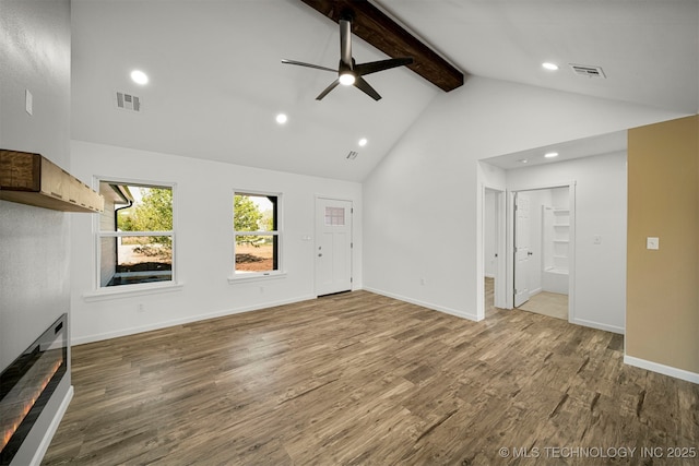 unfurnished living room with ceiling fan, beamed ceiling, wood-type flooring, and high vaulted ceiling