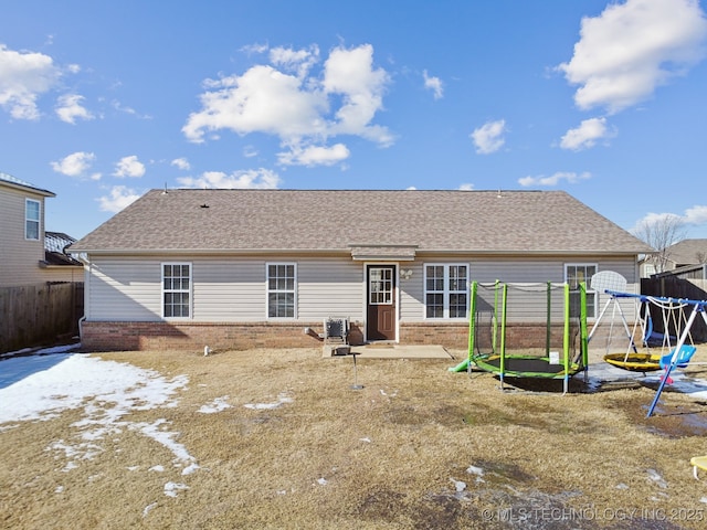 back of property featuring a playground and a trampoline