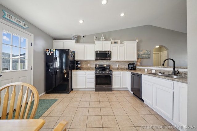 kitchen with sink, white cabinets, black appliances, and vaulted ceiling