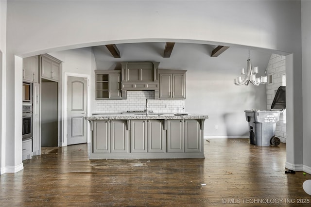 kitchen featuring an island with sink, stainless steel oven, dark hardwood / wood-style flooring, sink, and backsplash