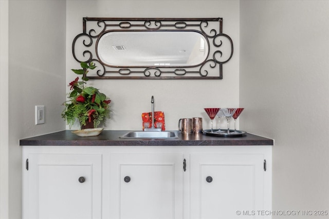 bar with white cabinets and sink