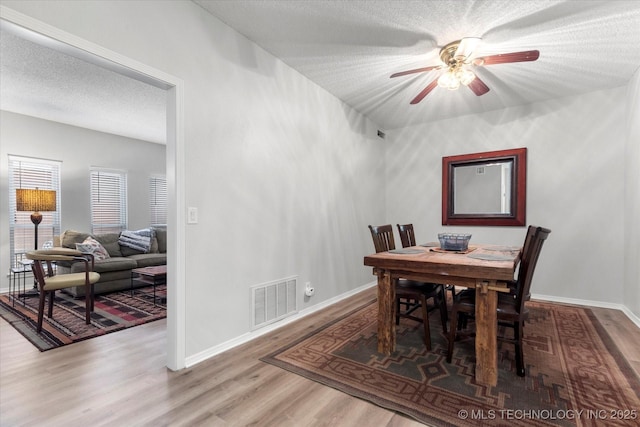 dining space with hardwood / wood-style floors, ceiling fan, and a textured ceiling