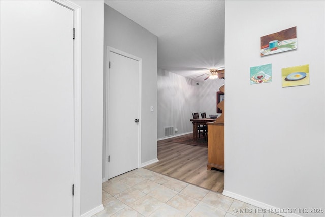 corridor featuring light tile patterned floors and a textured ceiling