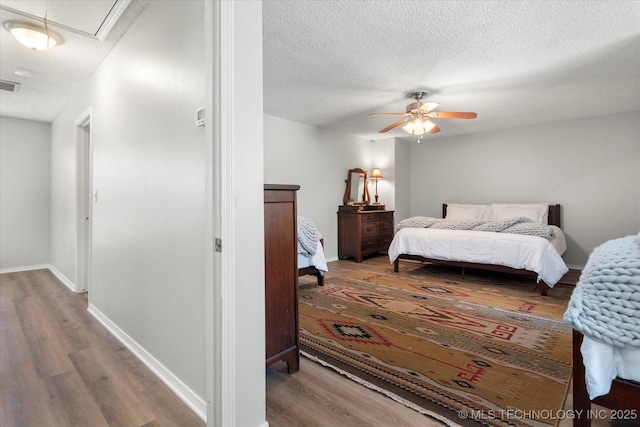 bedroom featuring wood-type flooring, a textured ceiling, and ceiling fan