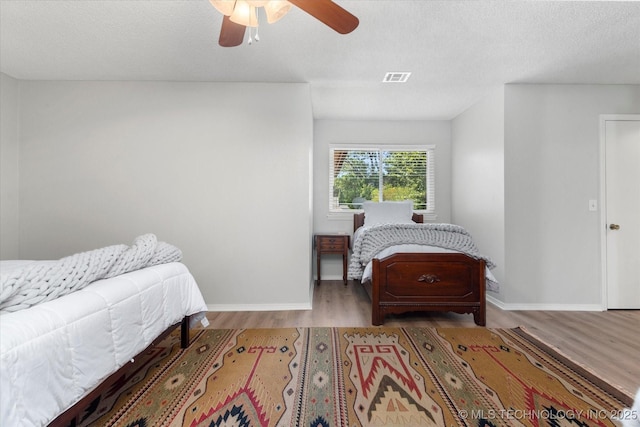 bedroom with ceiling fan, light hardwood / wood-style floors, and a textured ceiling