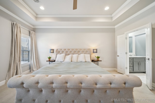 bedroom with a tray ceiling, ensuite bath, and ornamental molding