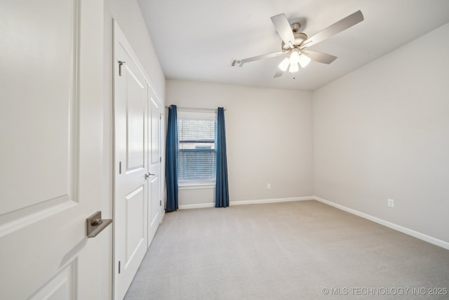 empty room featuring ceiling fan and light colored carpet