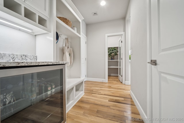 mudroom with light hardwood / wood-style flooring and beverage cooler