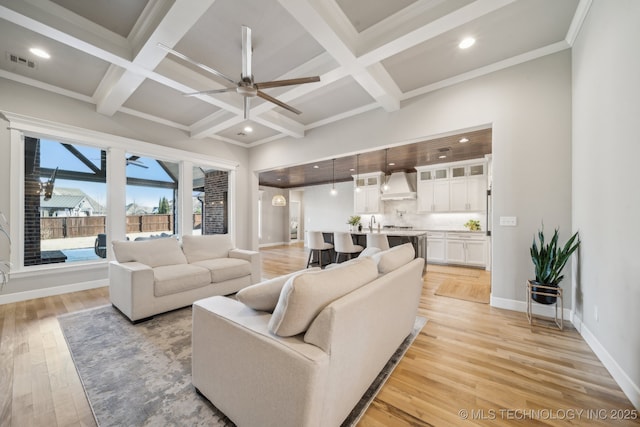 living room featuring beamed ceiling, light hardwood / wood-style floors, and coffered ceiling