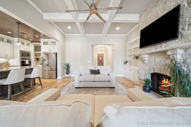 living room with a fireplace, beam ceiling, light hardwood / wood-style floors, and ceiling fan