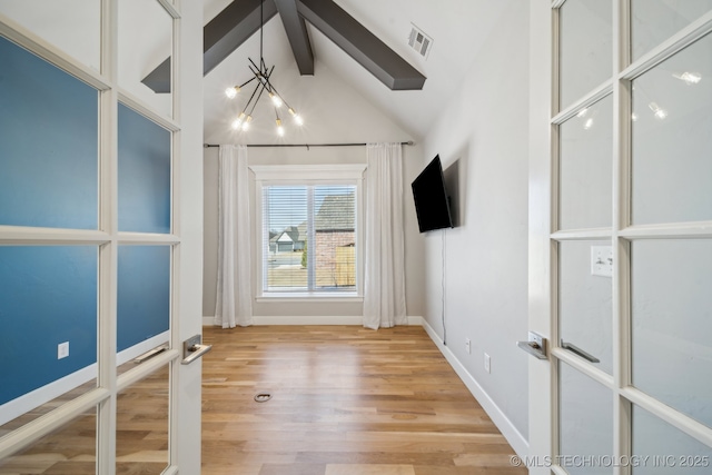 empty room featuring vaulted ceiling with beams, french doors, a chandelier, and light wood-type flooring