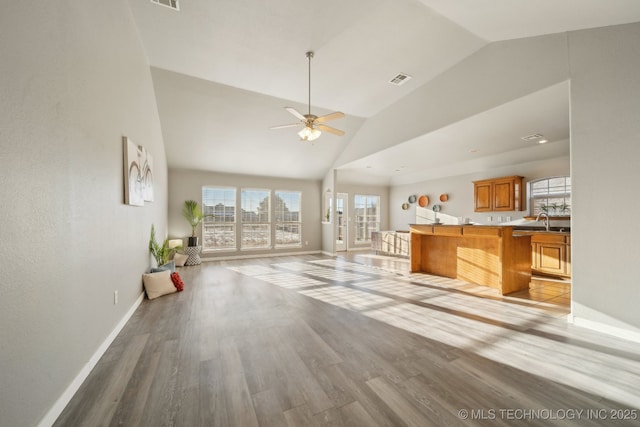 unfurnished living room featuring light hardwood / wood-style floors, ceiling fan, high vaulted ceiling, and sink