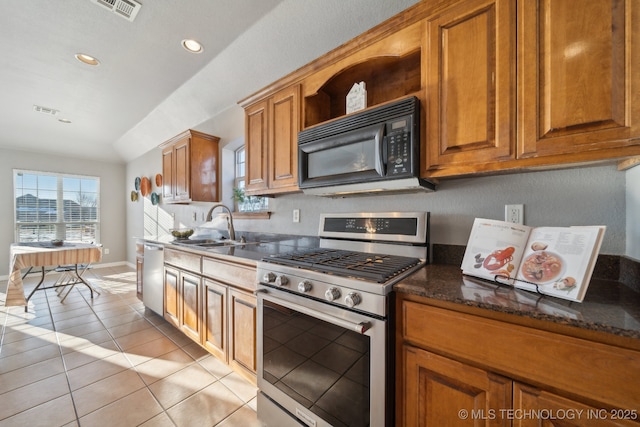 kitchen featuring dark stone countertops, appliances with stainless steel finishes, lofted ceiling, sink, and light tile patterned flooring