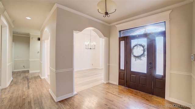 foyer featuring a chandelier, light wood-type flooring, and ornamental molding