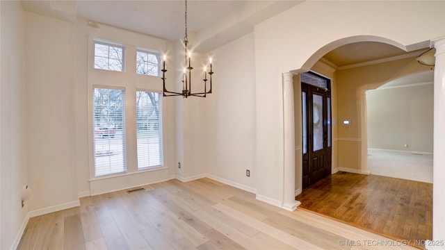 unfurnished dining area with ornamental molding, a chandelier, and wood-type flooring