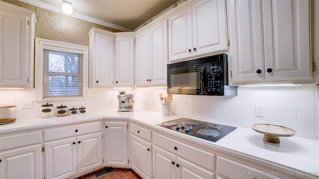 kitchen with white cabinets, decorative backsplash, ornamental molding, and black appliances