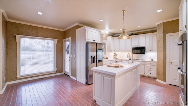 kitchen featuring decorative light fixtures, stainless steel appliances, a kitchen island with sink, and white cabinetry