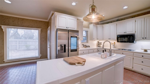 kitchen with a kitchen island with sink, tile counters, black appliances, white cabinets, and decorative light fixtures