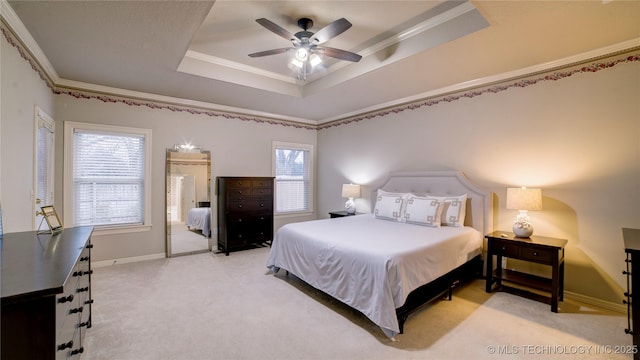 bedroom with ceiling fan, a tray ceiling, crown molding, and light carpet