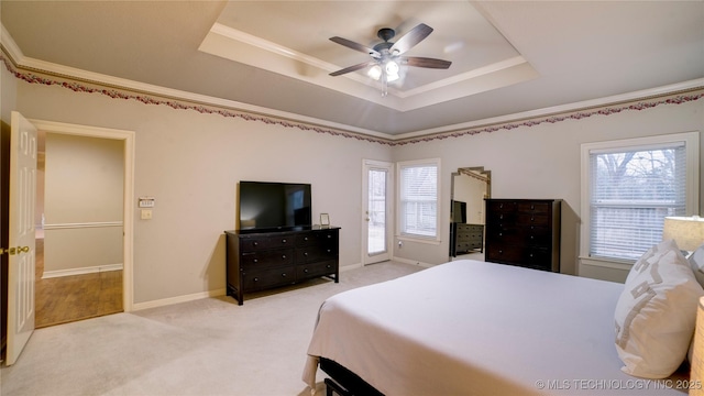 bedroom featuring ceiling fan, a tray ceiling, crown molding, and multiple windows