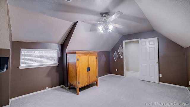 additional living space with ceiling fan, vaulted ceiling, light carpet, and a textured ceiling