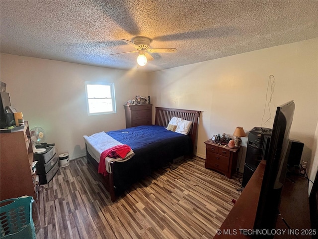 bedroom featuring ceiling fan, wood-type flooring, and a textured ceiling