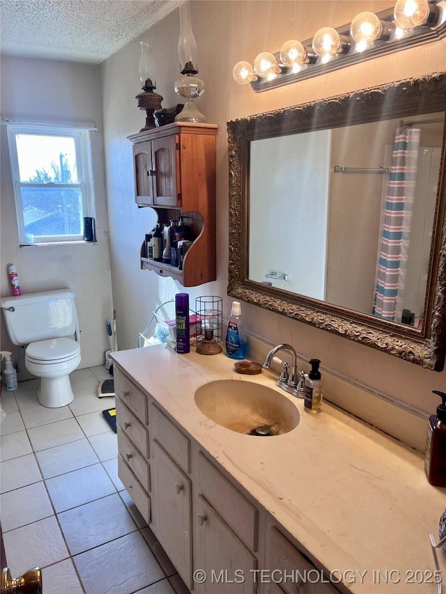 bathroom with toilet, vanity, a textured ceiling, and tile patterned floors