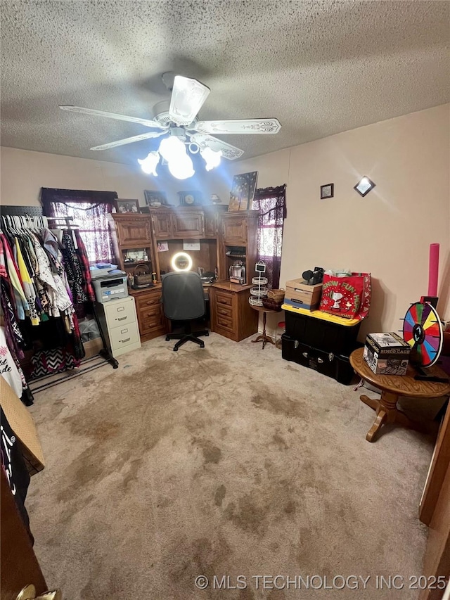 carpeted office space featuring a textured ceiling and ceiling fan